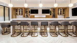 A modern kitchen with a bar area, wooden cabinets, and a herringbone floor pattern.
