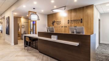 A reception desk with a wooden finish, two computer monitors, and a sign for Holiday Inn Express & Suites by IHG.
