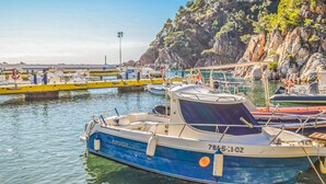 Una marina con imbarcazioni ormeggiate, scogliere rocciose e un edificio sulla collina.