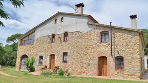 Una casa in pietra con un'ampia porta d'ingresso, diverse finestre e un camino.