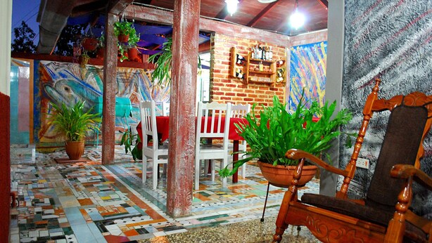 A cozy interior with a tiled floor, wooden furniture, and potted plants. - Casa Lourdes y Juan Jose (Viñales)