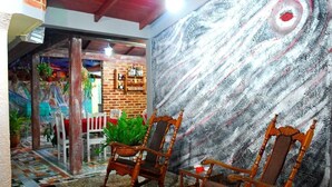 A room with two wooden rocking chairs, a brick wall, and a mural of a swirling galaxy. - Casa Lourdes y Juan Jose (Viñales)