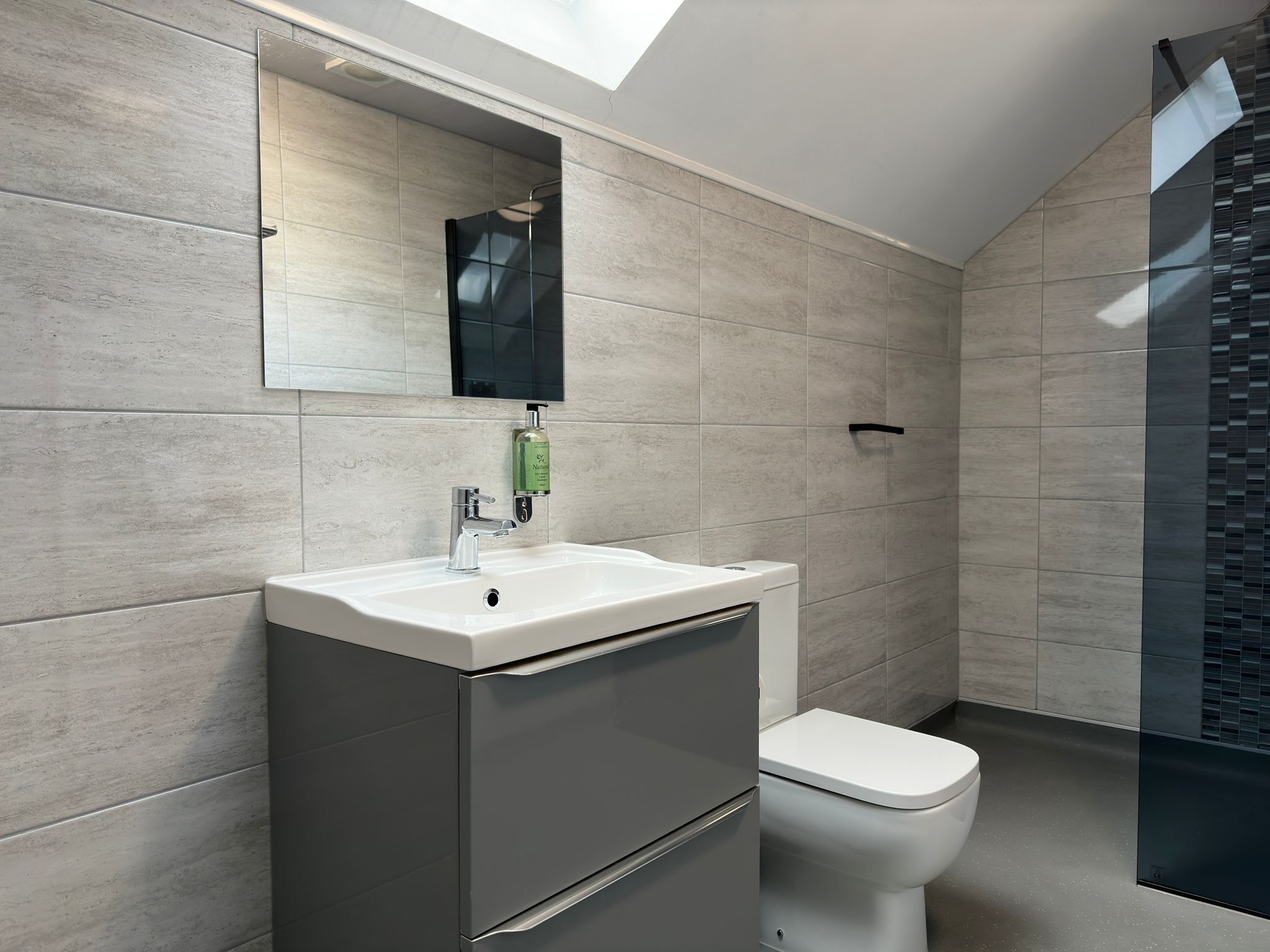 Un baño moderno con lavamanos blanco, un espejo y un inodoro.