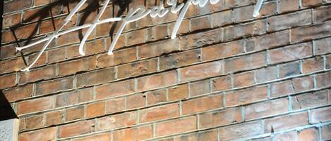 A brick wall with a neon sign spelling "Bennington Apartments."