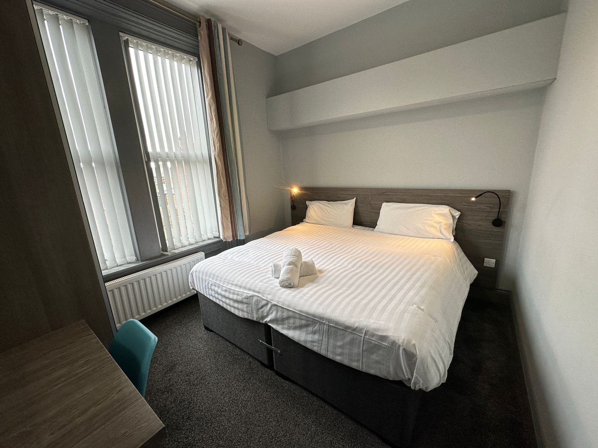 Une chambre d’hôtel avec un lit, un bureau et une chaise.