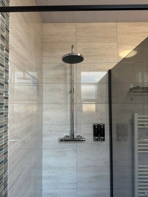 A modern shower with a rain showerhead, a handheld showerhead, and a towel rack. - Bentinck Apartments (Newcastle-upon-Tyne)