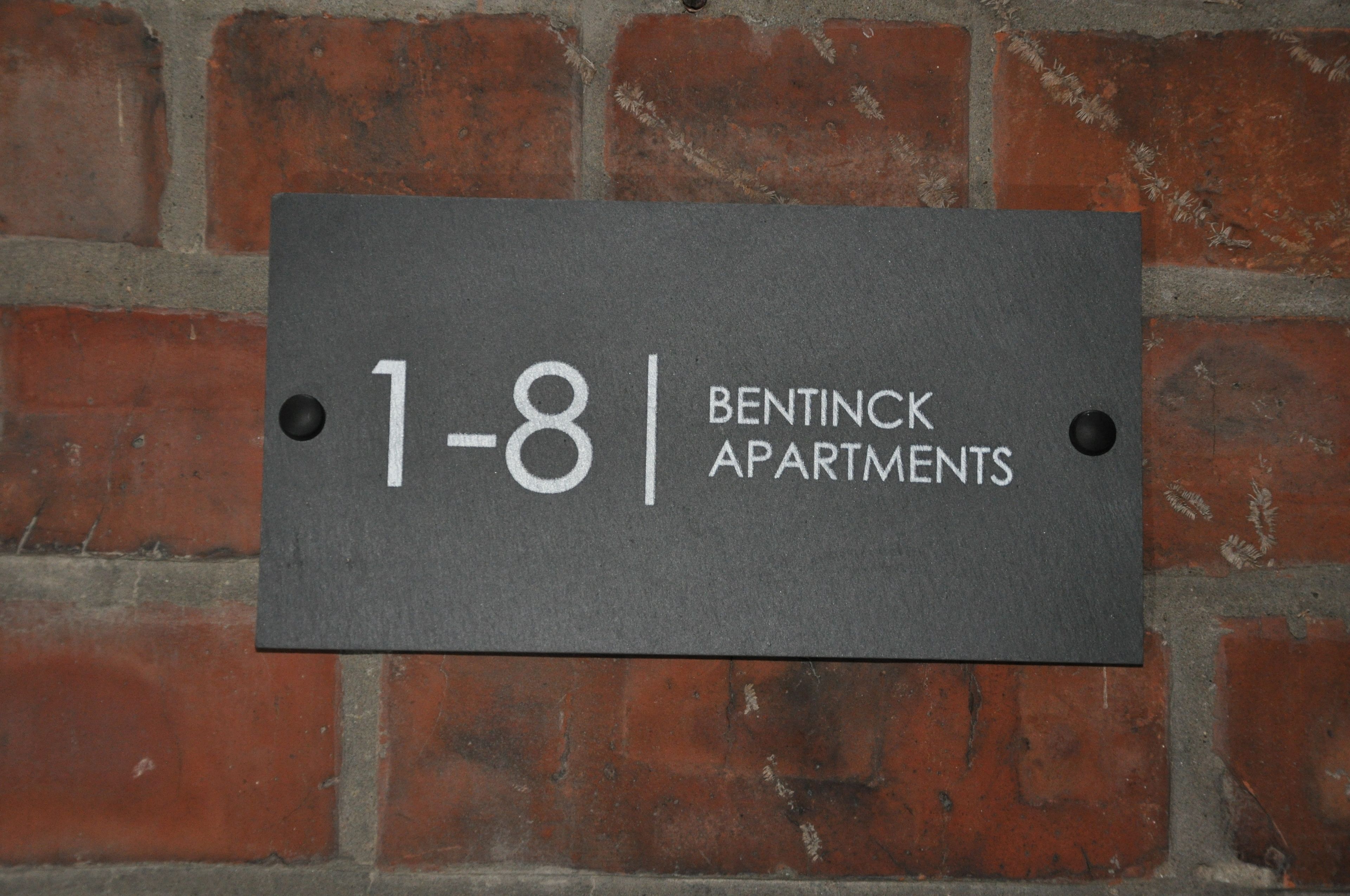 A sign for Bentink Apartments, indicating it is a residential building with apartment numbers 1-8.