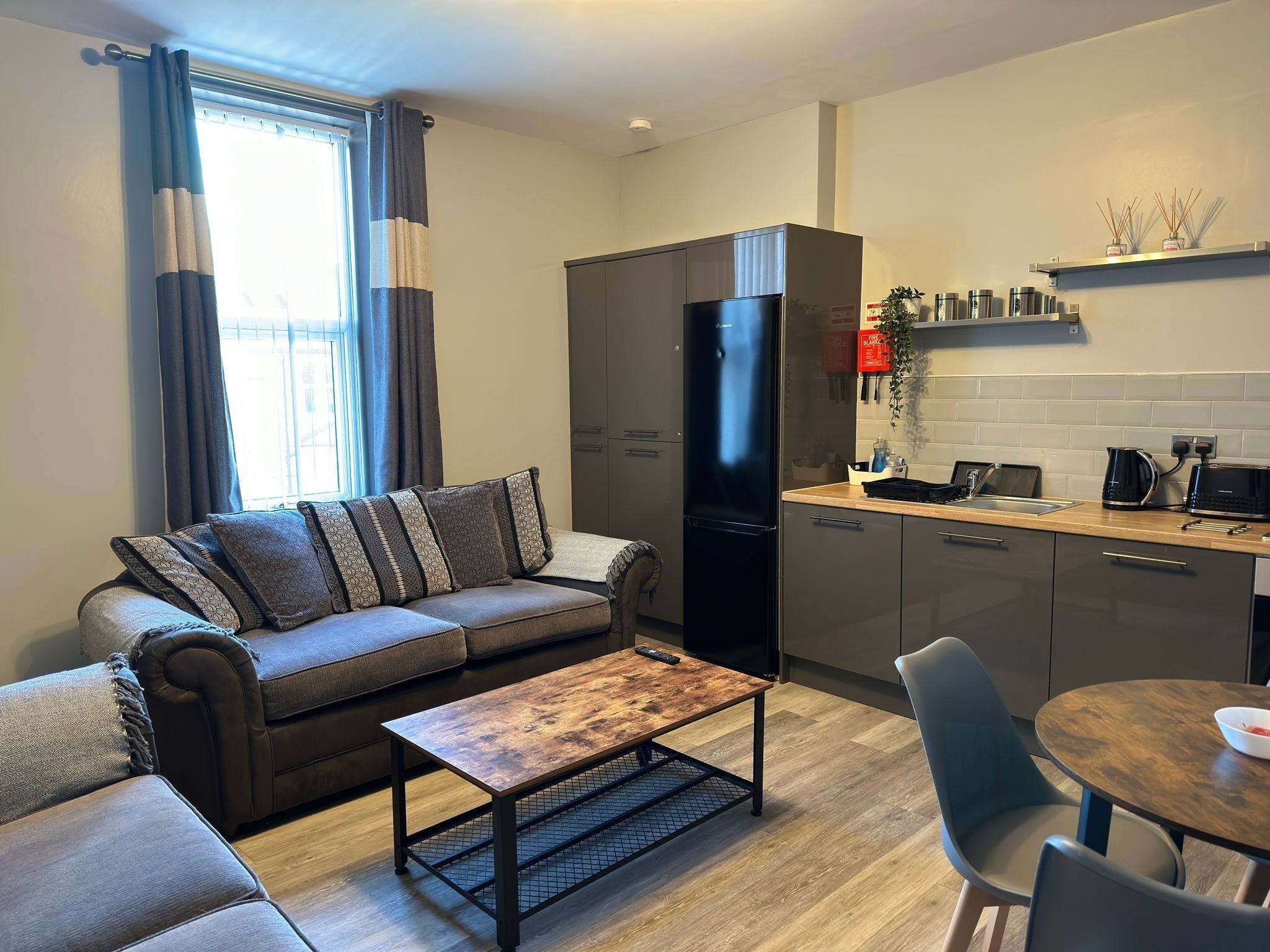 Un espacio habitable compacto con sofá, una mesa de centro, una mesa de comedor y una zona de cocina que incluye un refrigerador y un lavabo.