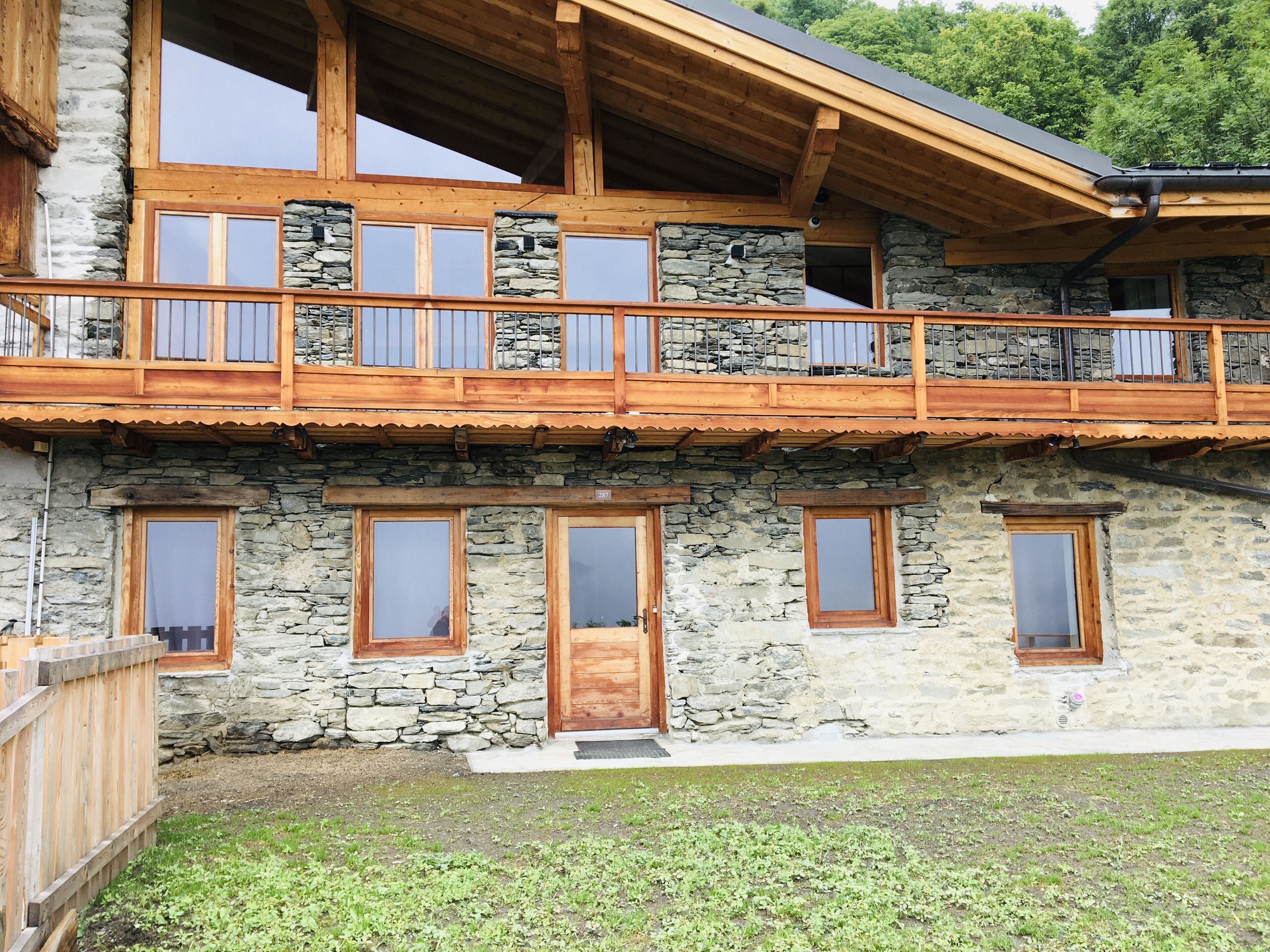 Un edificio in pietra di due piani con un balcone in legno e numerose finestre.