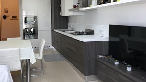 Une cuisine moderne équipée d’un four encastré, d’une cuisinière à gaz et d’un four à micro-ondes. Un coin repas avec une table et des chaises est également disponible.