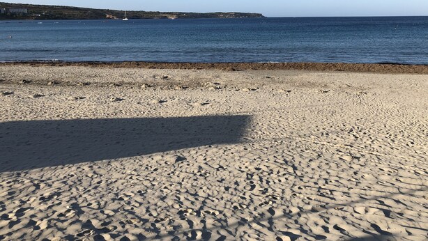 Une plage offrant une vue dégagée sur la mer et le lointain paysage terrestre.