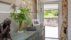 Et værelse med en antik trækommode, en vase med blomster, et indrammet fotografi og en statue.
