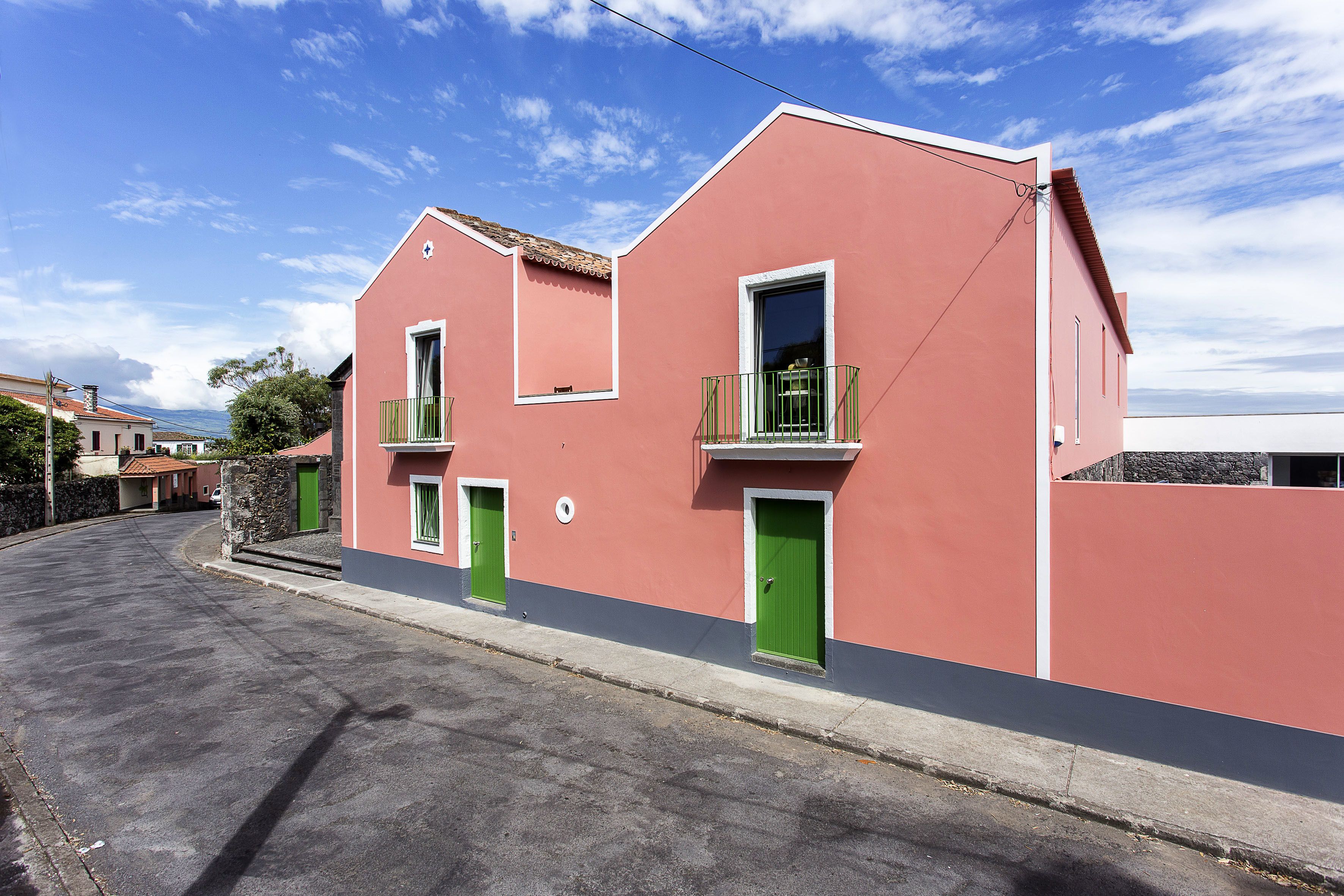 Un edificio rosa con un balcón y una puerta verde.