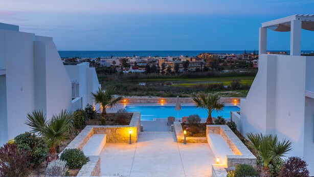 Ein Poolbereich eines Resorts mit Blick aufs Meer und die umliegenden Gebäude.