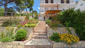 Un edificio de dos pisos con una escalera de piedra que conduce a una terraza de madera.