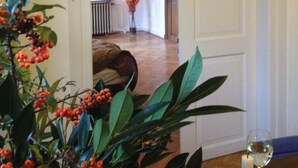An interior view of a room with a wooden floor, a white door, and a plant with orange berries. - Musikhaus Medebach. This historic house is in the village in Hochsauerland. (Medebach)