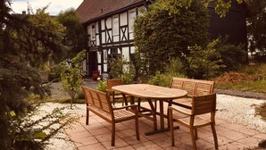 A traditional half-timbered house with a garden patio featuring a wooden table and chairs. - Musikhaus Medebach. This historic house is in the village in Hochsauerland. (Medebach)