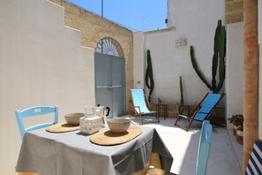Eine Terrasse im Freien mit einem Tisch für zwei Personen, einem blauen Stuhl und zwei Liegestühlen.