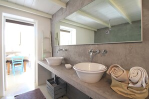 Ein Badezimmer mit zwei Waschbecken, einem großen Spiegel und Handtüchern auf einem Regal.