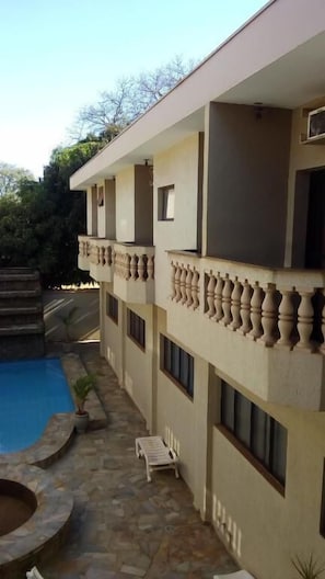 A multi-story building with a swimming pool, stone flooring, and a small garden area.