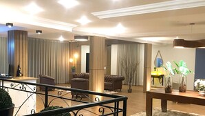 Una sala de estar moderna con un sofá, un sillón y una mesa de centro. Se observa una escalera con barandilla al frente.