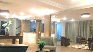 Una sala de estar moderna con un sofá, sillones, una mesa de centro y plantas decorativas.