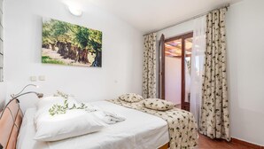Ein Schlafzimmer mit einem Bett, einem Nachttisch, einer Wandlampe und einem Fenster mit Vorhängen.