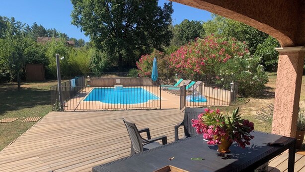 A wooden deck with outdoor furniture, a pool, and a garden with pink flowers. - Charming Provencal House - Private Pool - Near Lake & Beaches (Montauroux)