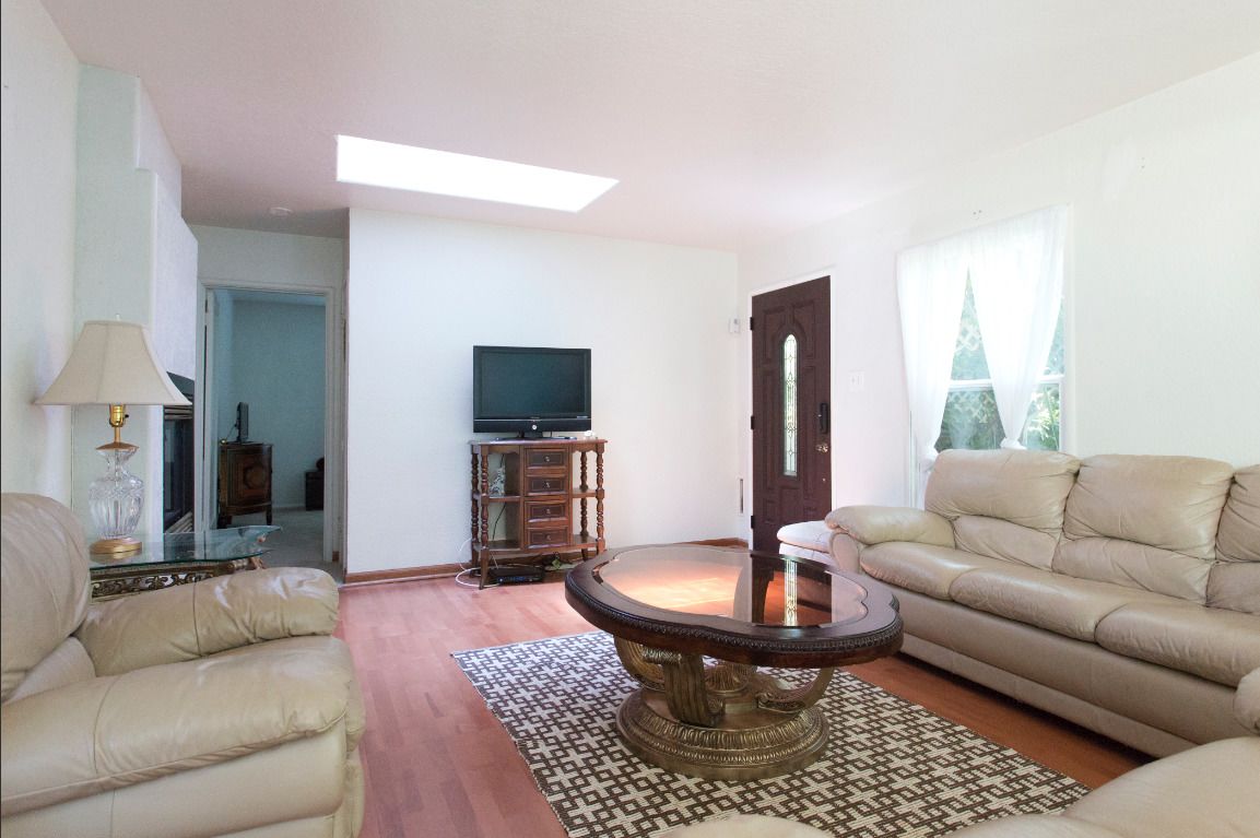 A living room with a sofa, a coffee table, a television, and a door.