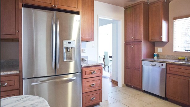A kitchen with wooden cabinets, a stainless steel refrigerator, a dishwasher, and a marble countertop. - Easy Bay Hidden Gem (Richmond)