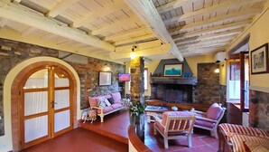 Una sala de estar acogedora con chimenea de piedra, un sofá rosa y techo de madera.