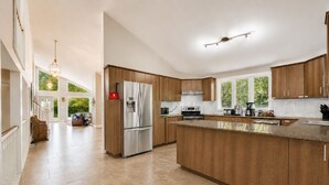 A spacious kitchen with wooden cabinets, a stainless steel refrigerator, and a large island. - Lakefront Lake Simcoe Retreat | Private Dock, Hot Tub & Sandy Shore (Georgina)