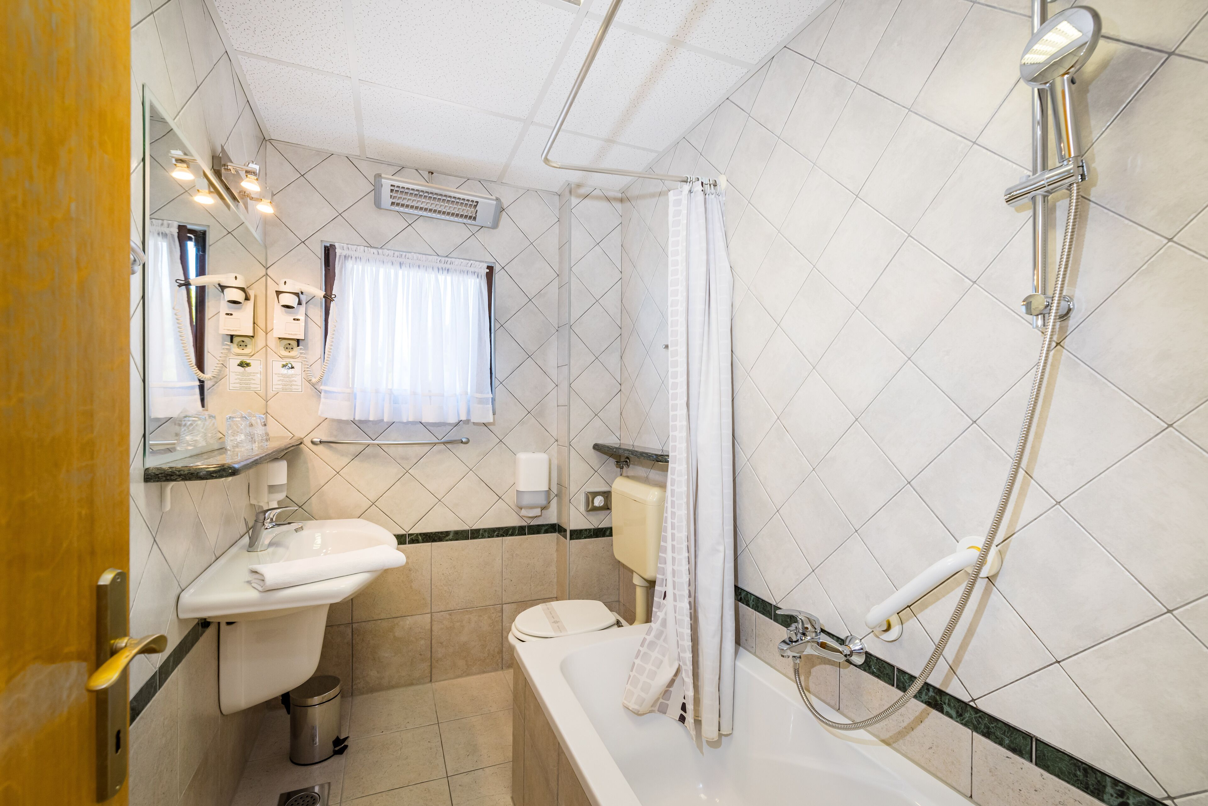 A bathroom with a toilet, sink, shower, and a mirror.