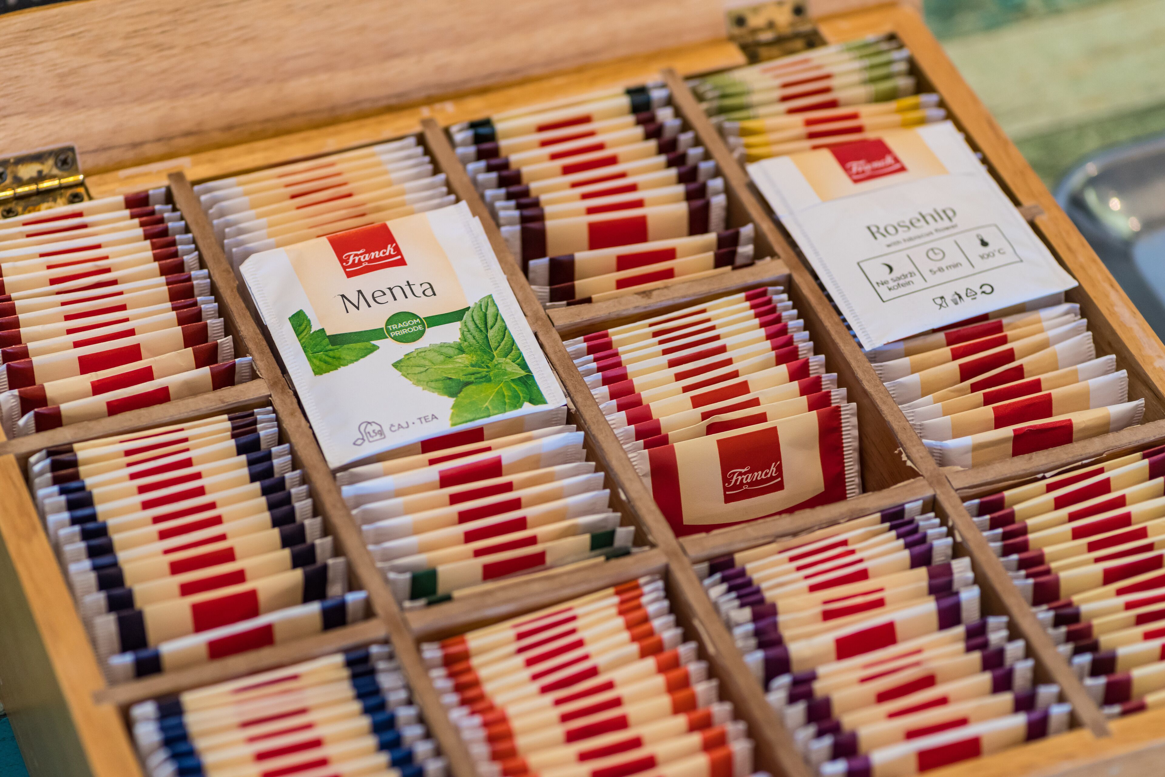 Una caja de madera con varios paquetes de té organizados por color.