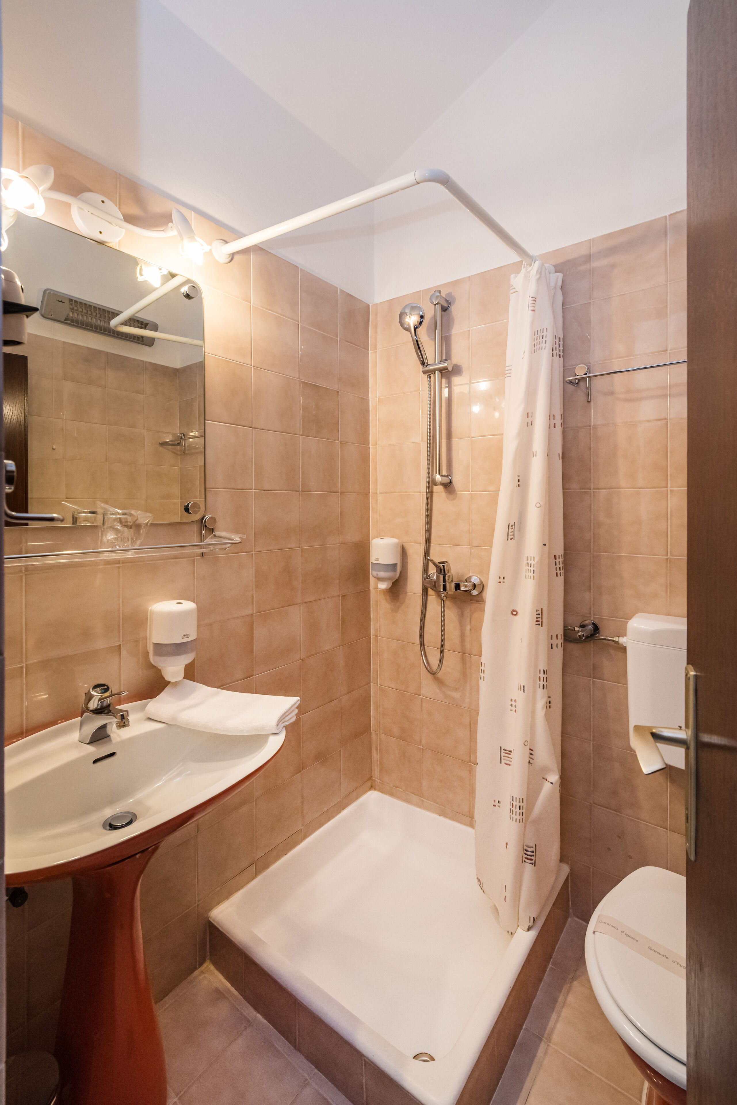 Une salle de bain comprenant un lavabo sur colonne, une baignoire, une douche avec une porte en verre et des toilettes.