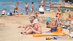 A beach scene with people sunbathing and swimming. - Hotel Vicko (Starigrad)