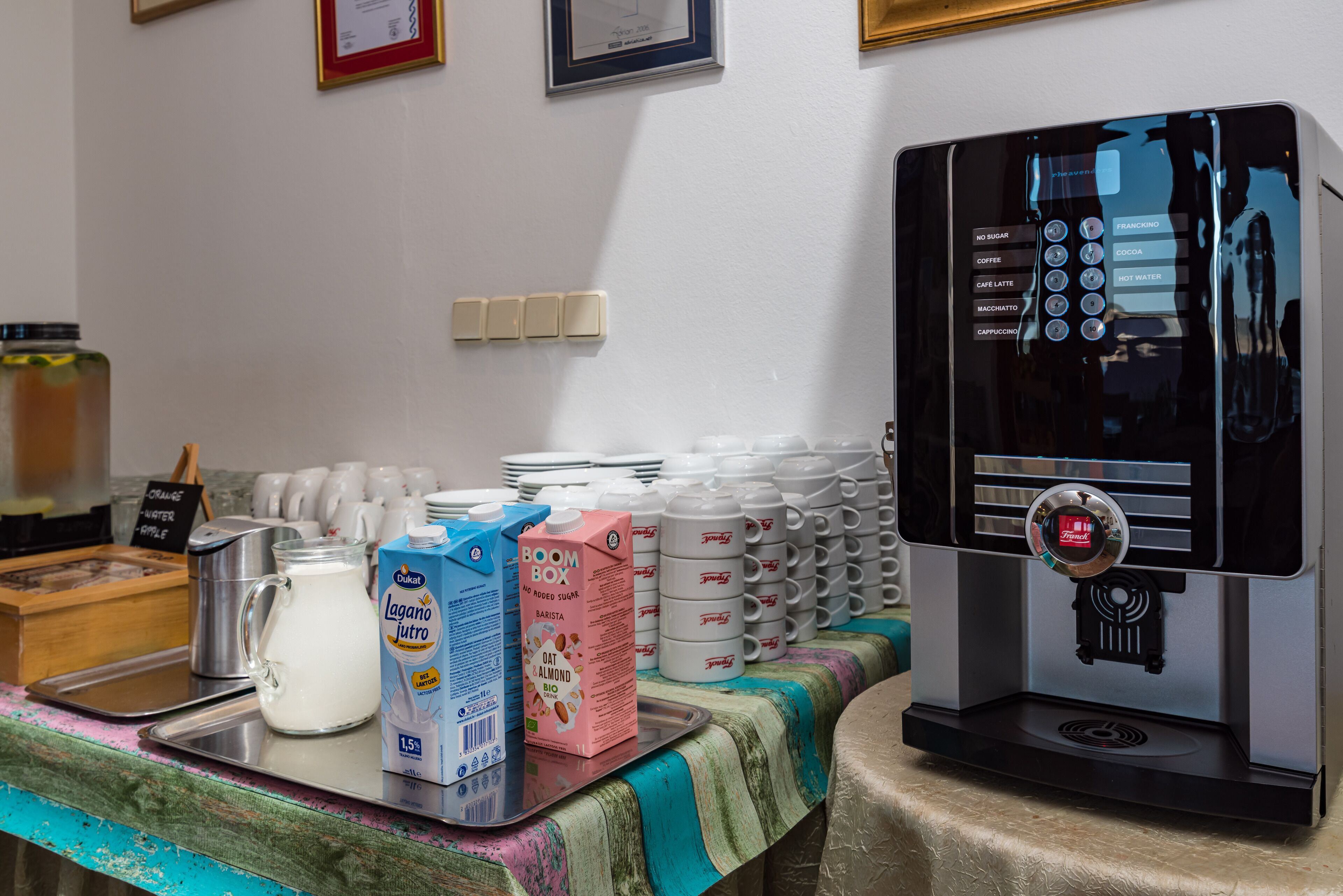A coffee station with a coffee machine, milk cartons, and coffee cups.