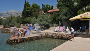 A coastal resort with a pool area, lounge chairs, and a view of the sea and mountains. - Hotel Vicko (Starigrad)