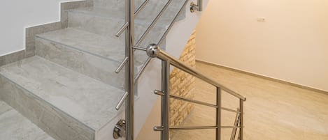 A multi-level interior with a staircase featuring metal railings and marble steps.