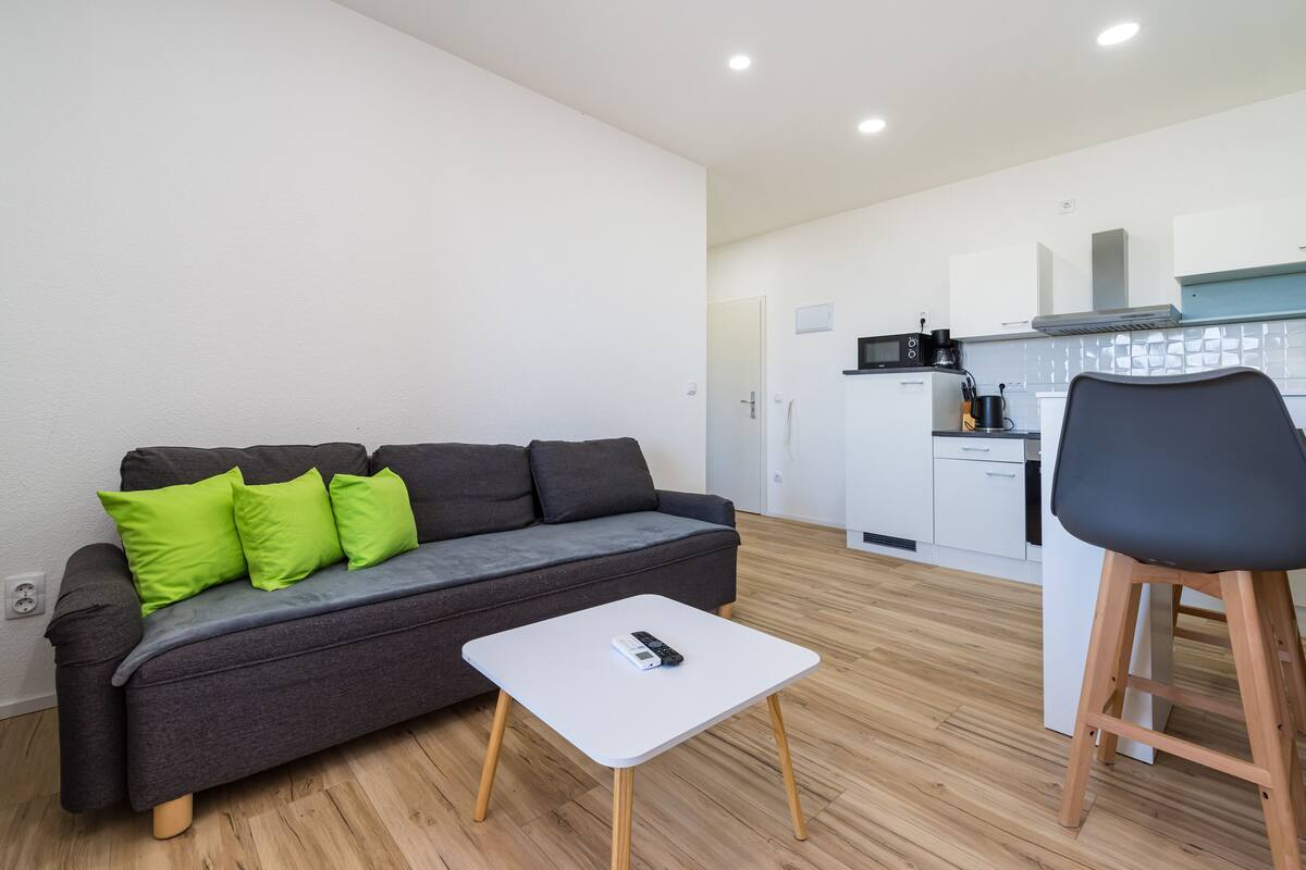 A modern living room with a grey sofa, a white coffee table, and a black chair.