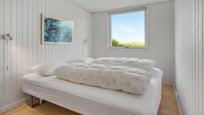 Ein Schlafzimmer mit Bett, Fenster, Gemälde und Lampe.