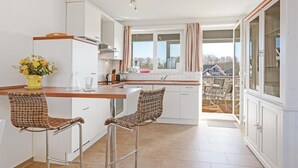 A modern kitchen with white cabinets, a wooden countertop, and two wicker chairs. - 1 bedroom stunning apartment in Rechlin (Rechlin)