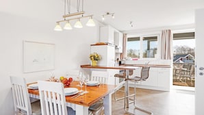 A modern kitchen with white cabinetry, a wooden dining table, and a view of the outside. - 1 bedroom stunning apartment in Rechlin (Rechlin)