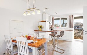 A modern kitchen with white cabinetry, a wooden dining table, and a view of the outside. - 1 bedroom stunning apartment in Rechlin (Rechlin)