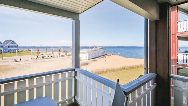 A balcony with a view of the beach, a building, and a pier. - 1 bedroom stunning apartment in Rechlin (Rechlin)