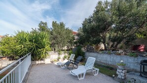 A patio with white lounge chairs, a stone wall, and a variety of plants. - JOSIP 1, 3 bedroom apartment, 230m from beach  (Okrug Gornji)