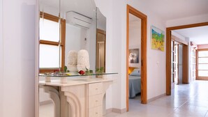 Ein modernes Badezimmer mit Duschkabine aus Glas, einem großen Spiegel und einem Waschtisch mit Glasplatte.