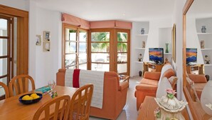 Ein Wohnzimmer mit Essbereich, Holzmöbeln, einer Couch, einem Couchtisch und einem Fernseher.