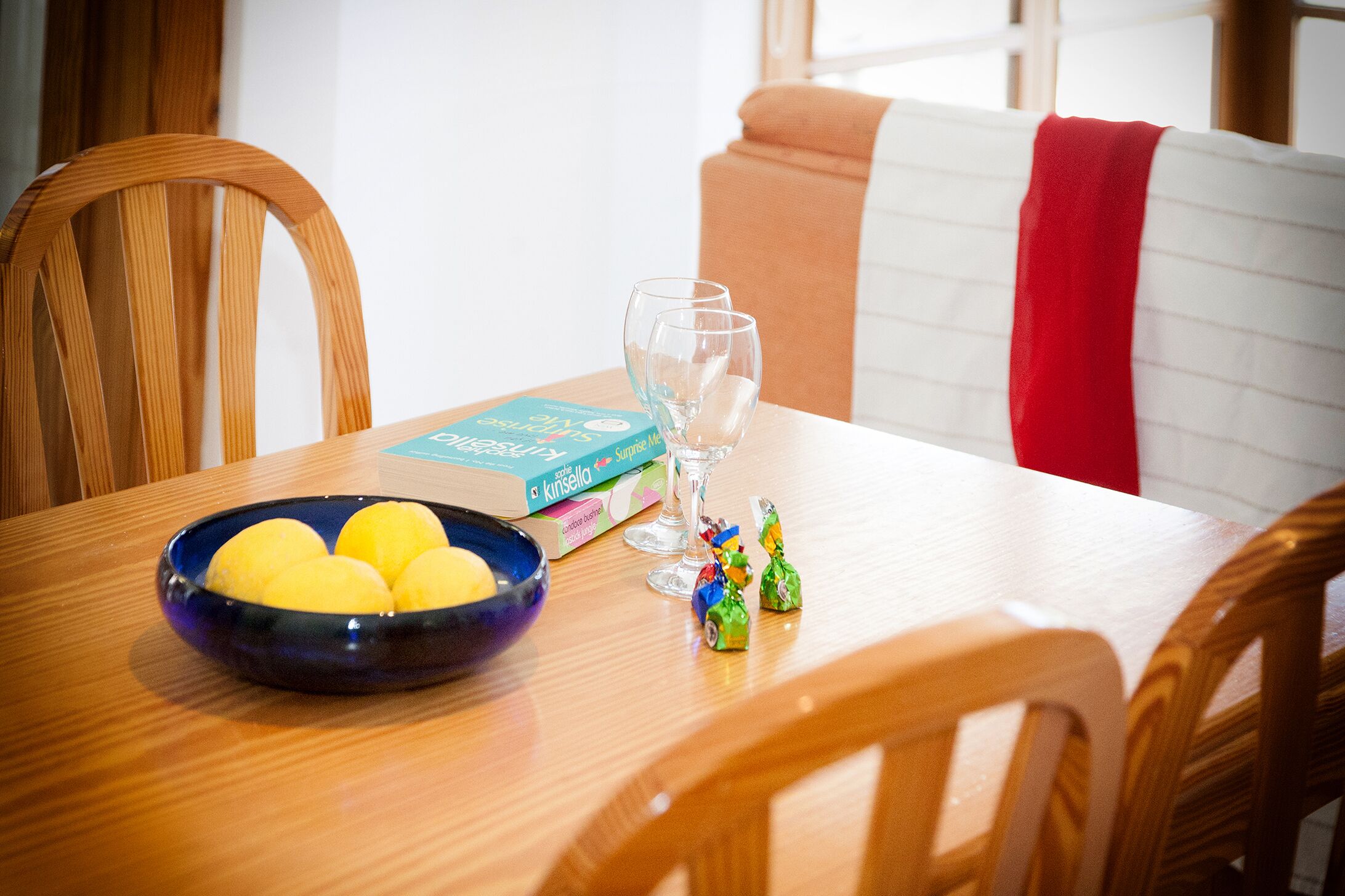 Una mesa con un cuenco de limones, una caja de limones y una copa de vino.