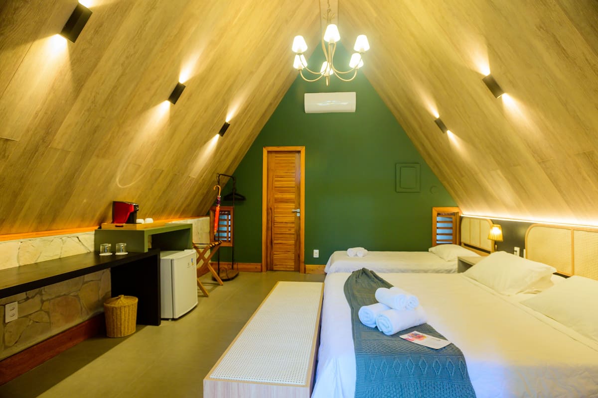 A cozy attic bedroom with a sloped ceiling, a small kitchenette, and a bed with neatly folded towels.